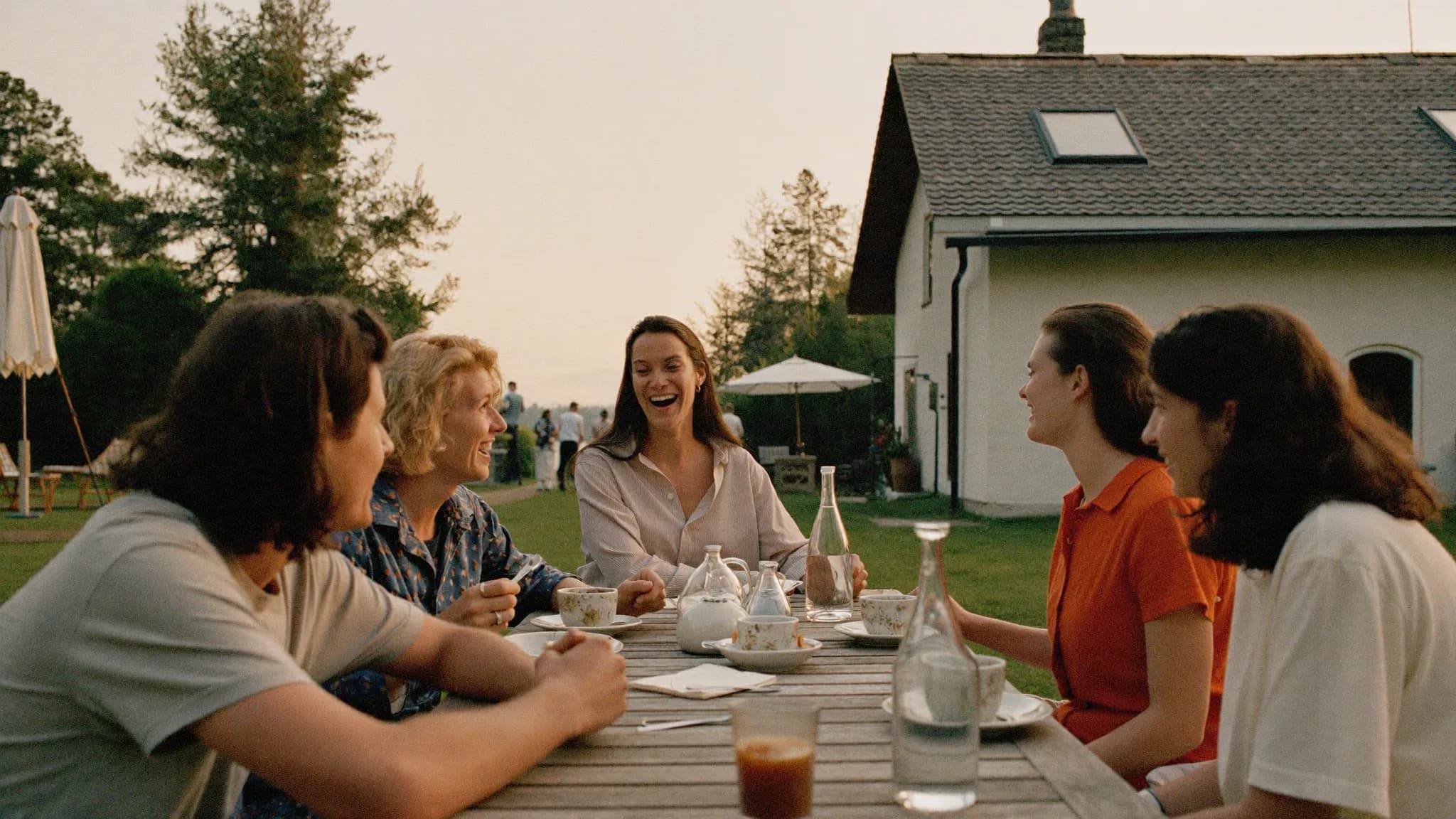Vriendengroep aan een lange tafel bij een vakantiehuis in de avondzon